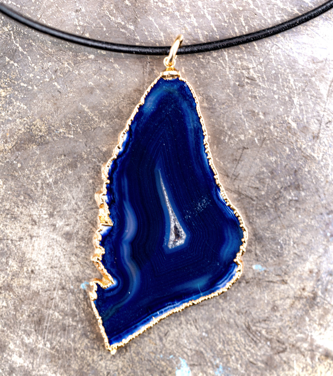 Blue agate pendant with 14K gold wrap and 1.5MM black leather cord necklace against a gray metal background