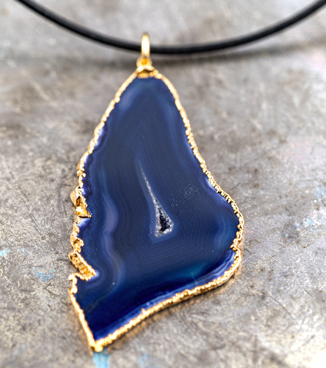 Blue agate pendant with 14K gold wrap and 1.5MM black leather cord necklace against a gray metal background