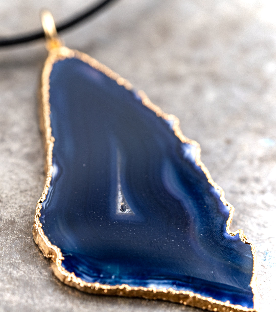 Blue agate pendant with 14K gold wrap and 1.5MM black leather cord necklace against a gray metal background